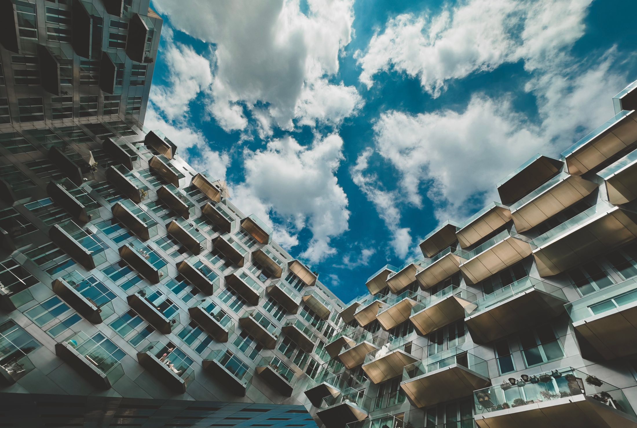 Apartment buildings with projecting balconies surrounding a cloudy blue sky
