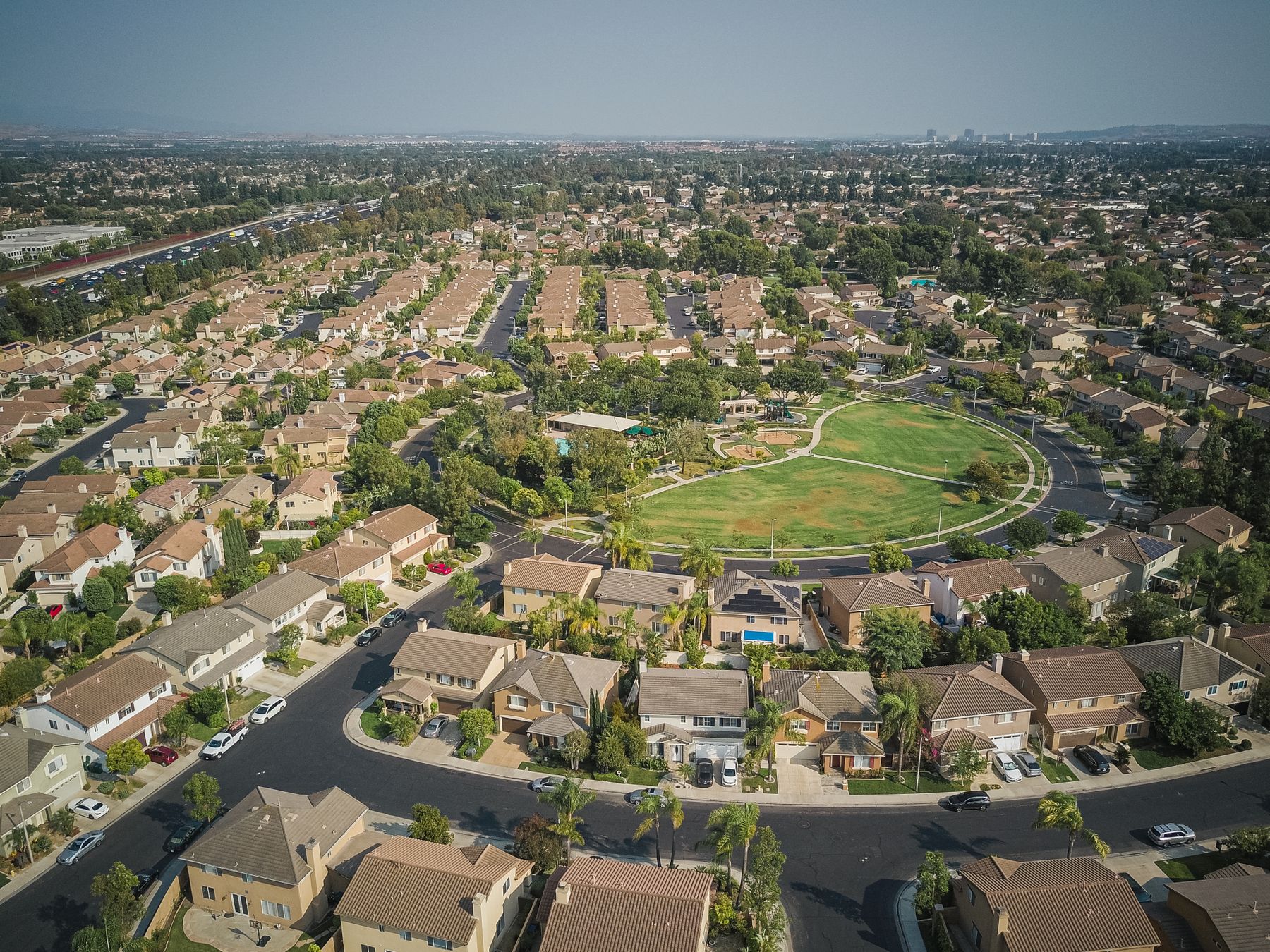 Aerial view of suburban houses and streets surrounding a green park